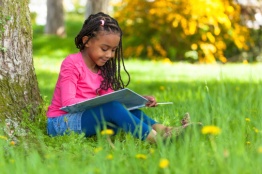 Cute young black little girl reading a book